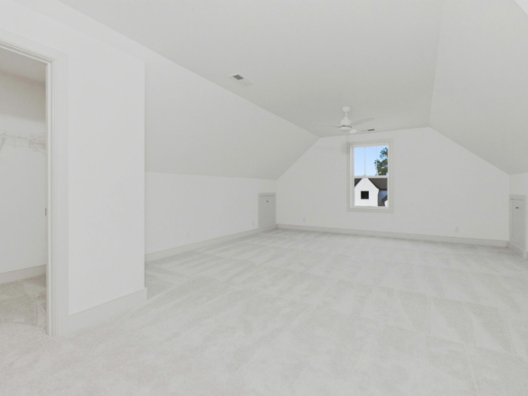 Empty white room with a vaulted ceiling, ceiling fan, and a small window showing a house outside on the right side of the room.