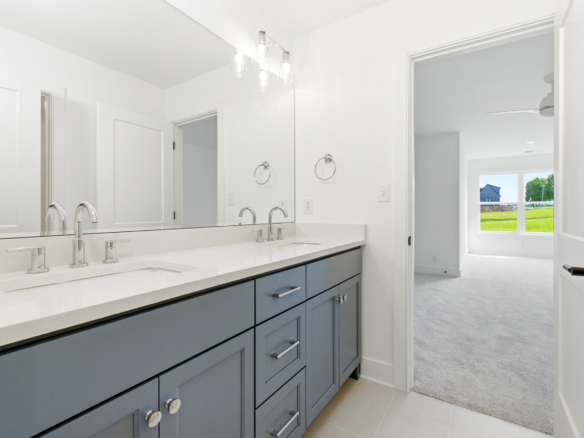 Modern bathroom with white countertops, dual sinks, and blue-gray cabinets beneath a large mirror.