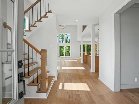 Bright, open interior with hardwood floors and staircase at Mason Construction & Development.