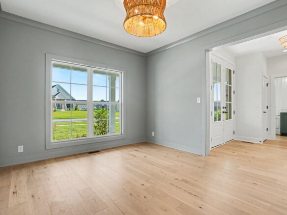 Bright living room with large window and light wood flooring in a new home.