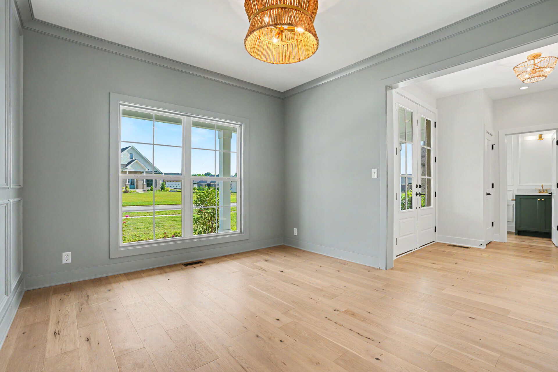Bright living room with large window and light wood flooring in a new home.