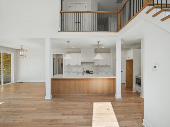 Open-concept kitchen with white cabinets and wooden island in a modern home.