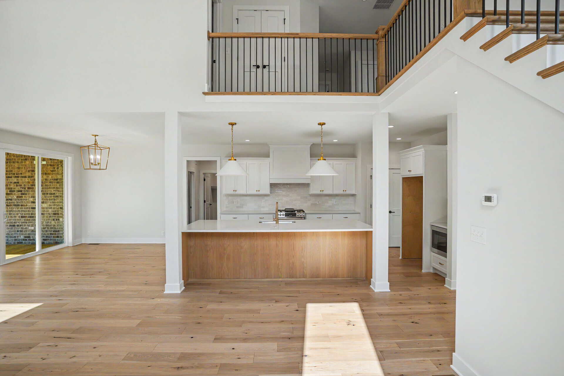 Open-concept kitchen with white cabinets and wooden island in a modern home.