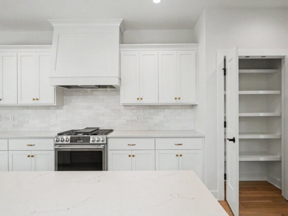 Modern white kitchen with cabinets, stove, and pantry in Louisville, KY.