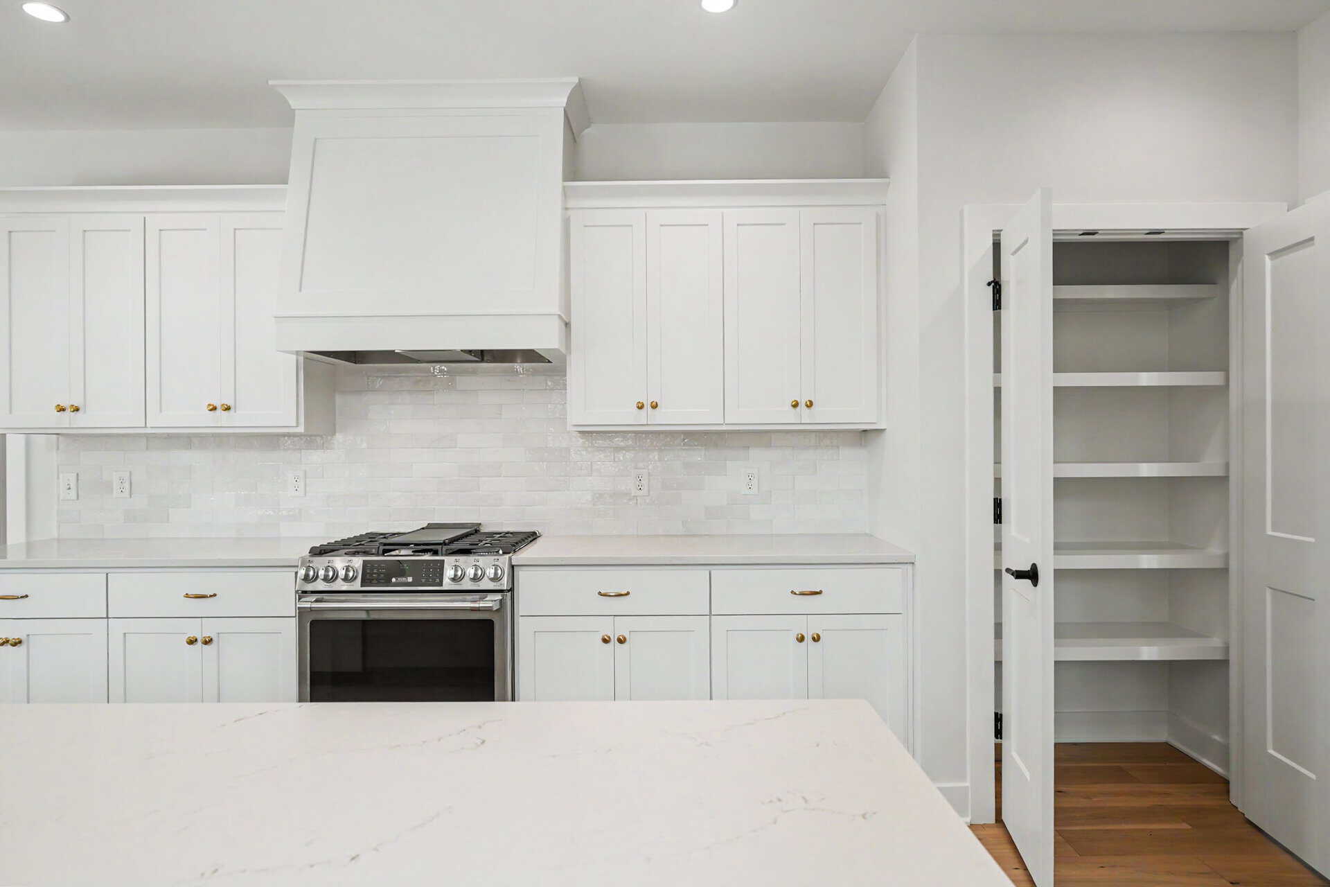 Modern white kitchen with cabinets, stove, and pantry in Louisville, KY.