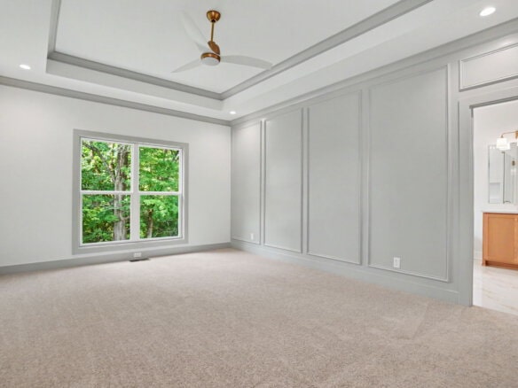 Spacious empty room with large window, white walls, and ceiling fan.