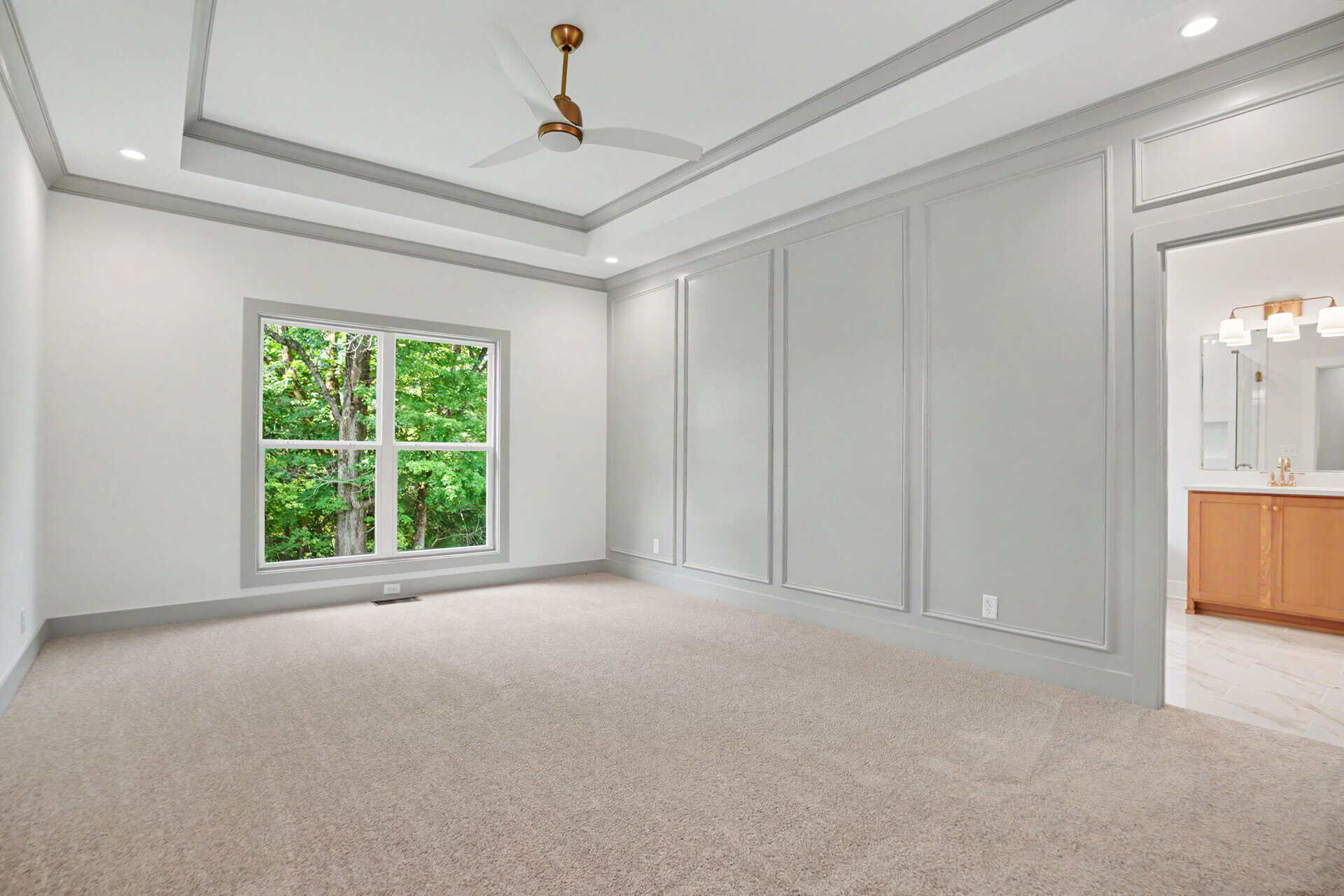 Spacious empty room with large window, white walls, and ceiling fan.