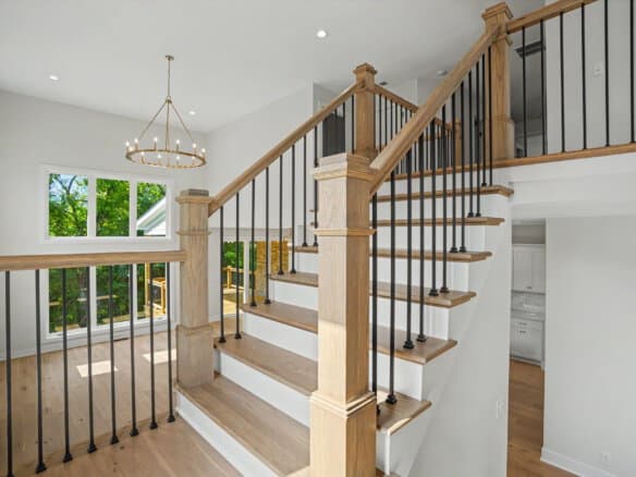 Modern staircase with wooden handrails and black metal balusters in a bright home.