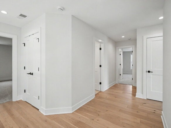 Bright, modern hallway with white walls and hardwood flooring in a new home.