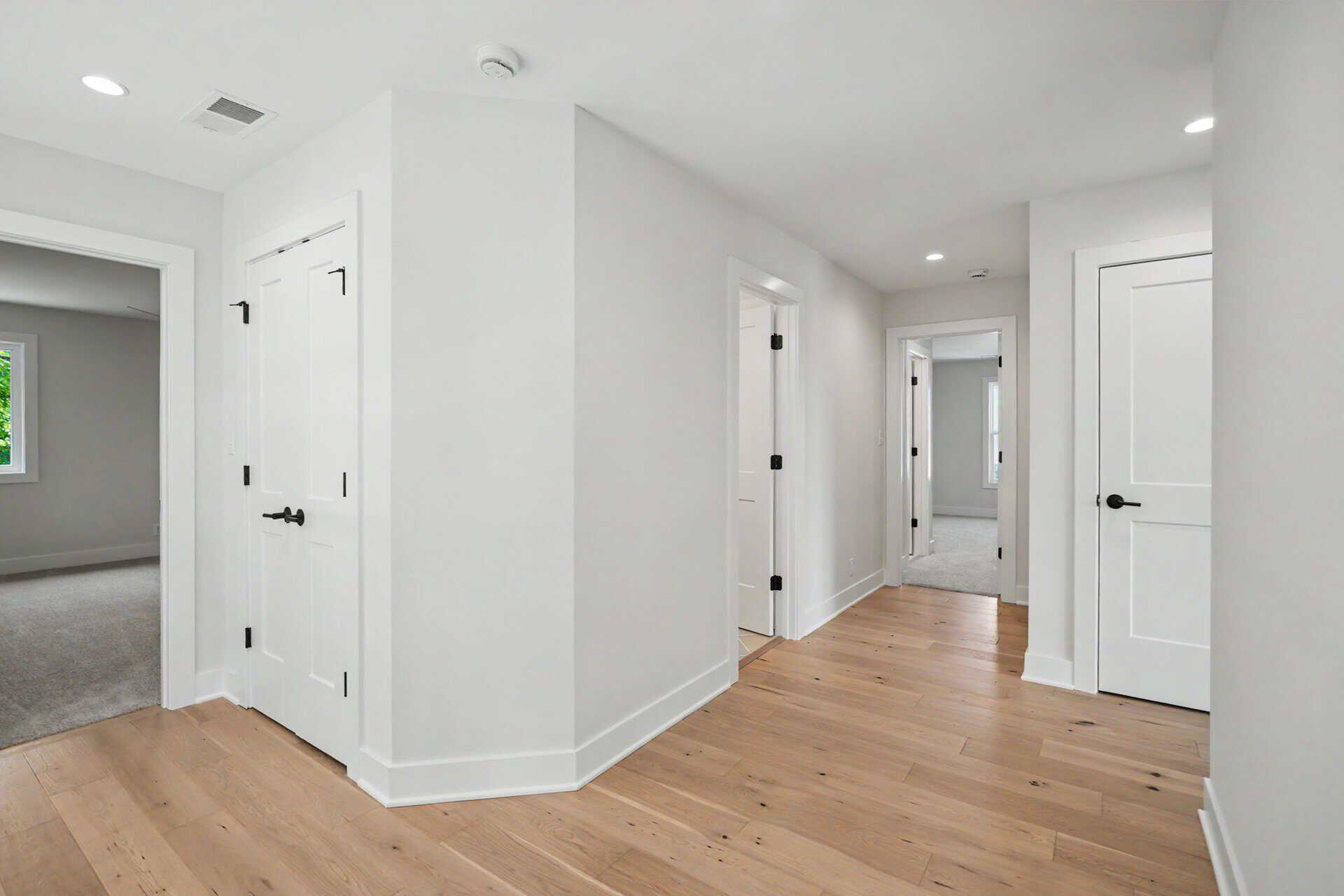 Bright, modern hallway with white walls and hardwood flooring in a new home.