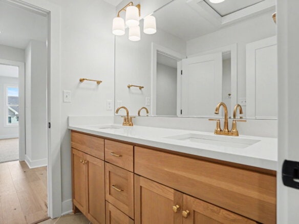 Modern bathroom vanity with double sinks and gold fixtures in a bright space.