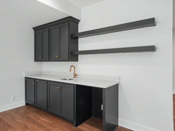 Kitchen with dark gray cabinetry, white countertop, and a gold-toned faucet; two long dark metal wall brackets extend from the upper cabinet area.