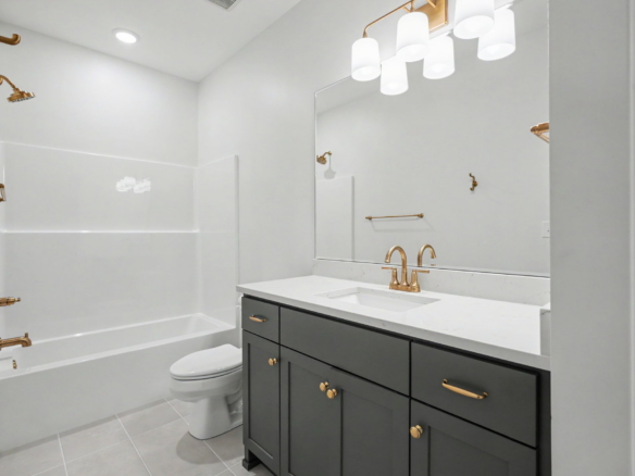 Modern bathroom with a white bathtub, glass shower, and gray vanity topped with white marble; gold fixtures and a large mirror.
