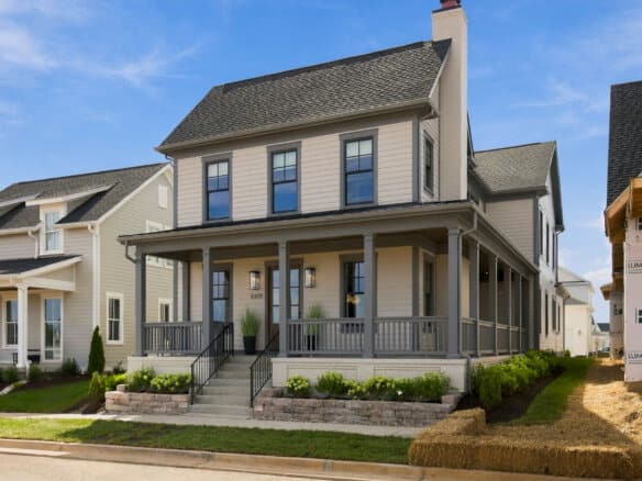 Newly built two-story home with a large front porch and landscaped yard.