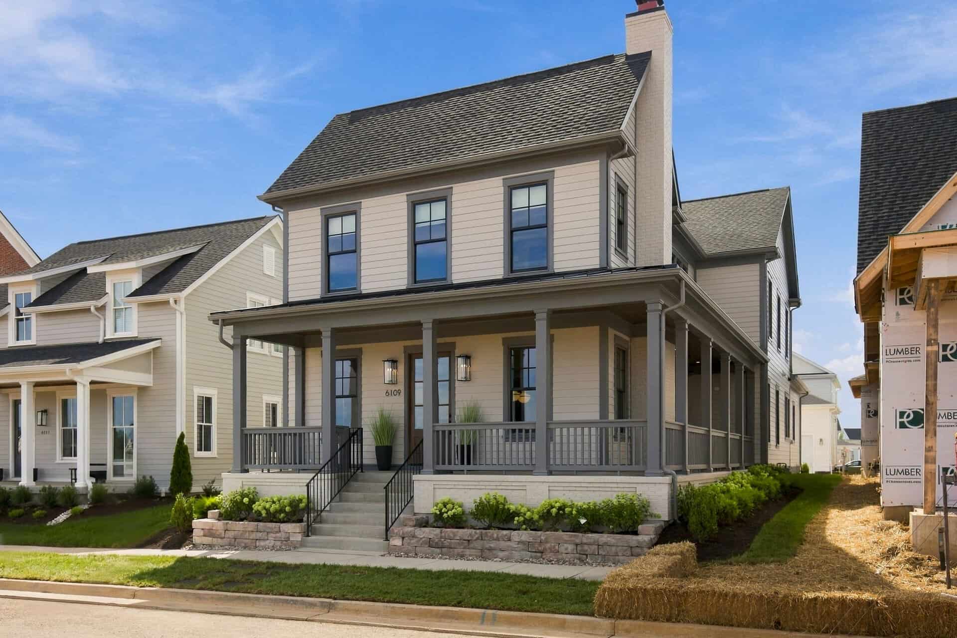 Newly built two-story home with a large front porch and landscaped yard.