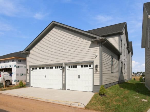 Newly built modern house with a double garage and beige siding in Louisville, KY.