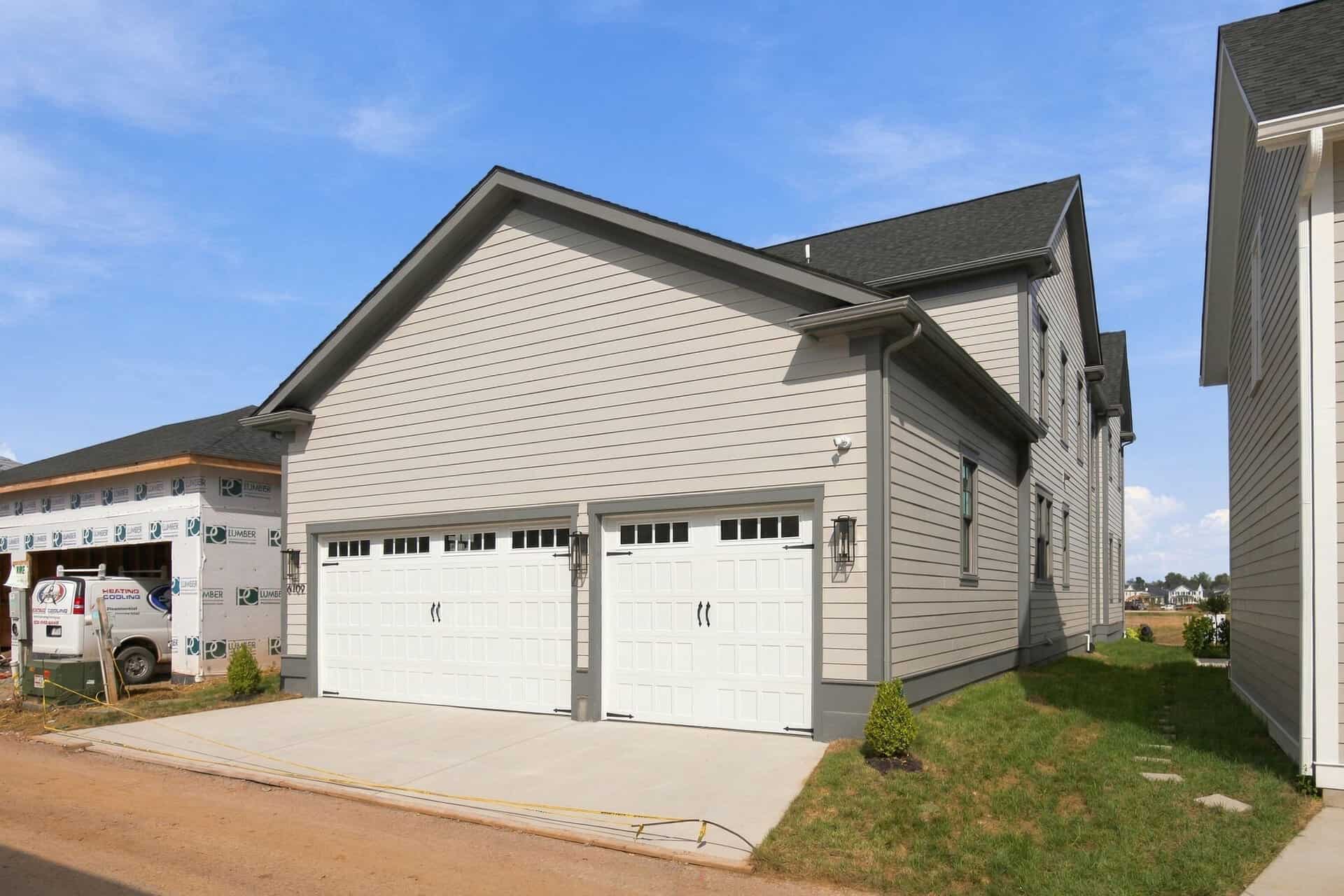 Newly built modern house with a double garage and beige siding in Louisville, KY.