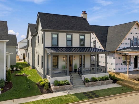 Newly built modern home with a covered front porch and landscaped yard in Louisville, KY.