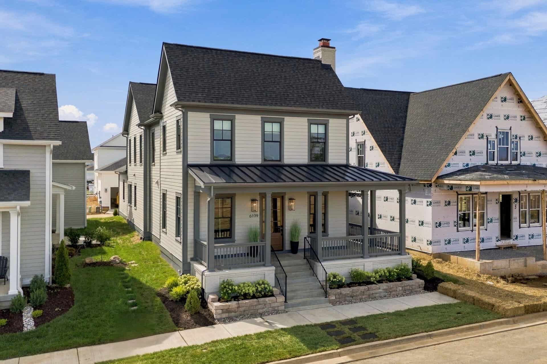 Newly built modern home with a covered front porch and landscaped yard in Louisville, KY.