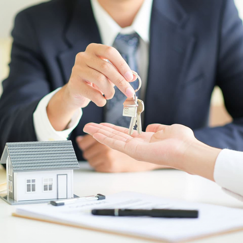 Real estate agent handing over house keys to new homeowner.